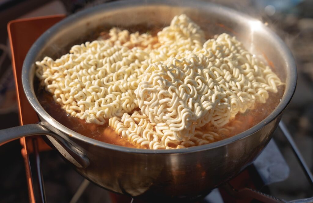 アウトドア用バーナーで鍋にインスタントラーメンを調理している様子