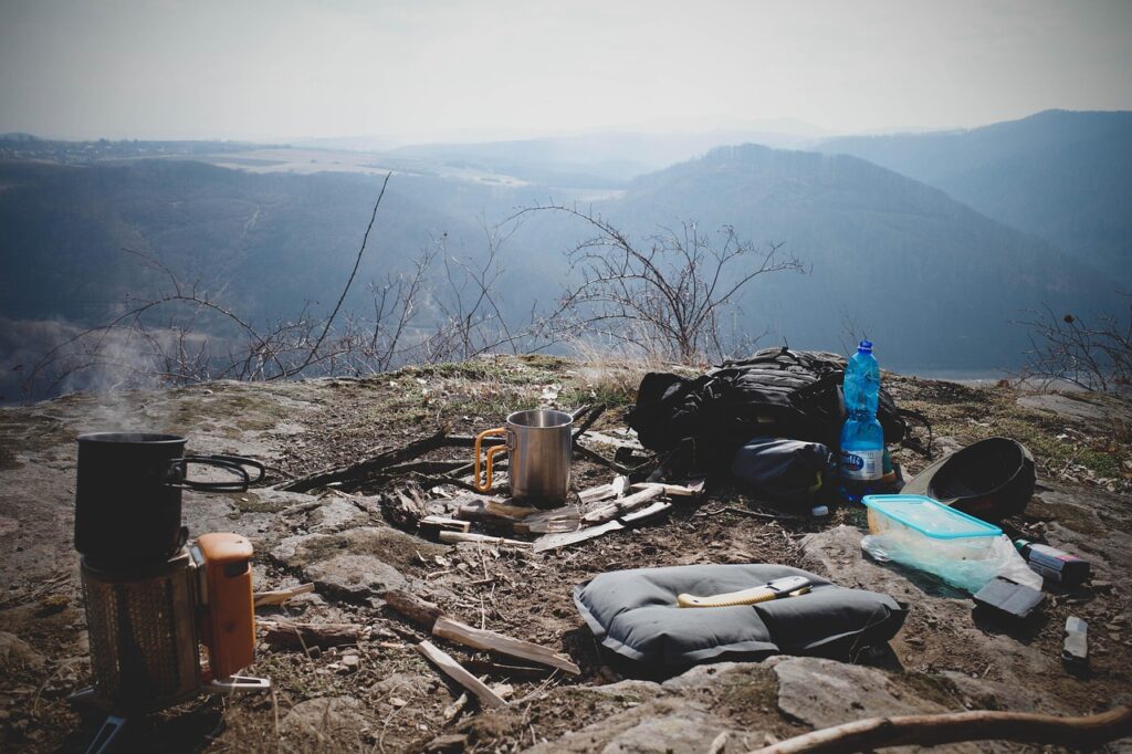 山頂付近で調理器具やバックパックを広げたソロキャンプの設営風景