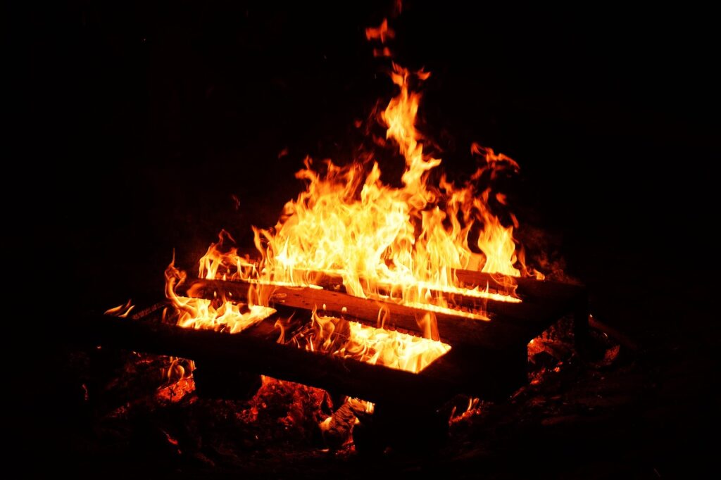 夜の暗闇の中で薪が燃え上がる焚き火の様子