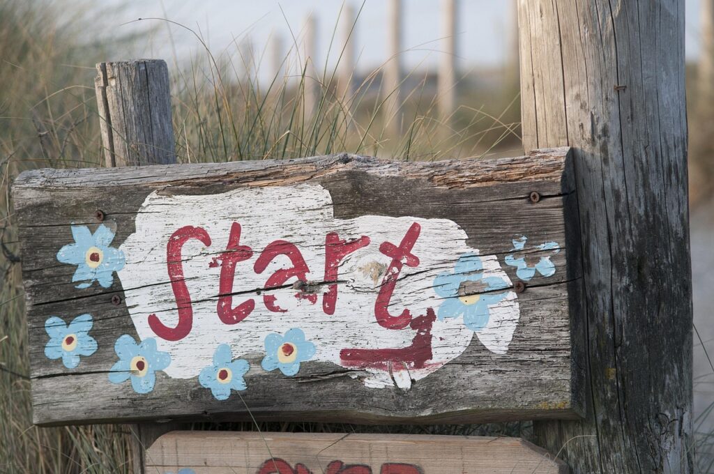 「Start」と書かれた花の装飾がある木製の案内看板