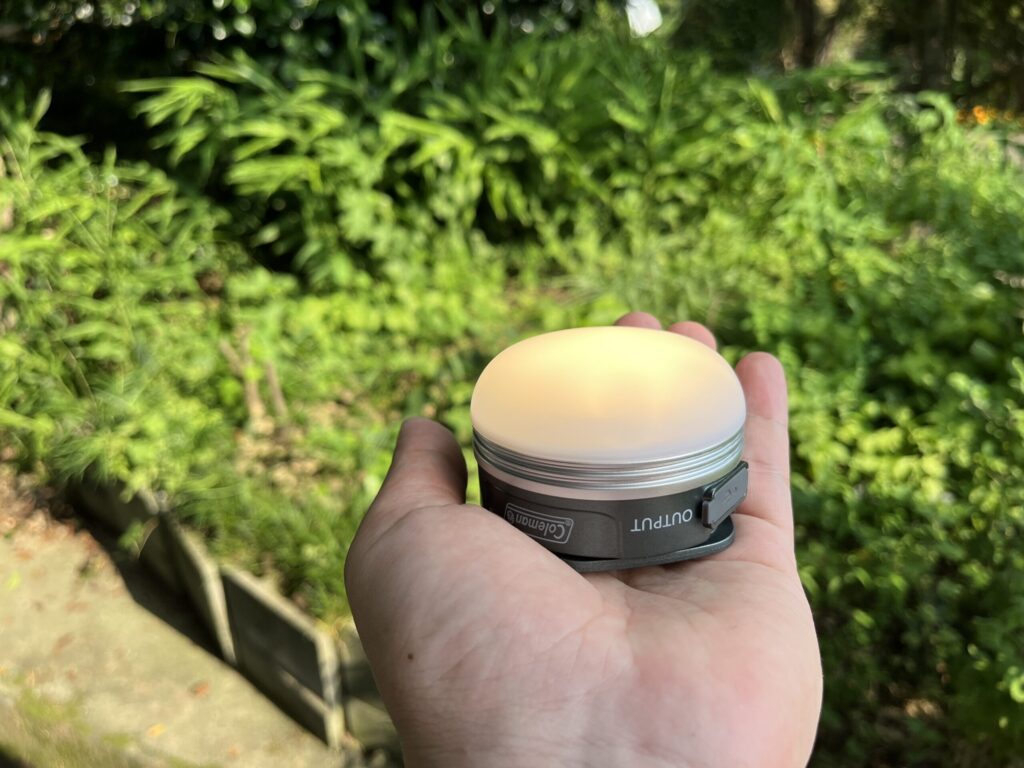 点灯したColemanの充電式ミニランタンを手のひらに載せた様子。