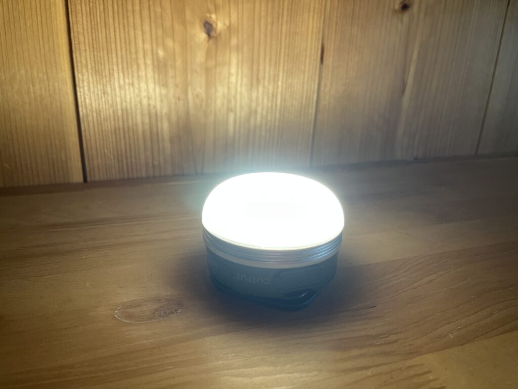 点灯したColemanの充電式ミニランタンを木製テーブルの上に置いた様子。