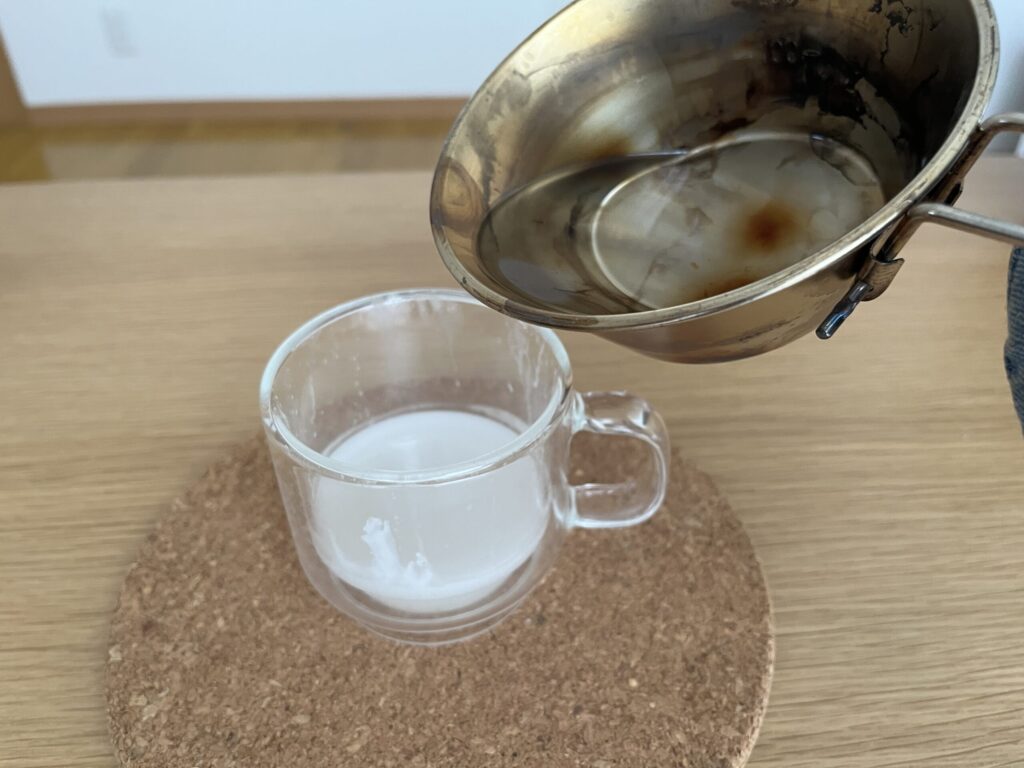 溶かしたソイワックスをガラス容器に注ぎ、アロマキャンドルを作っている様子。