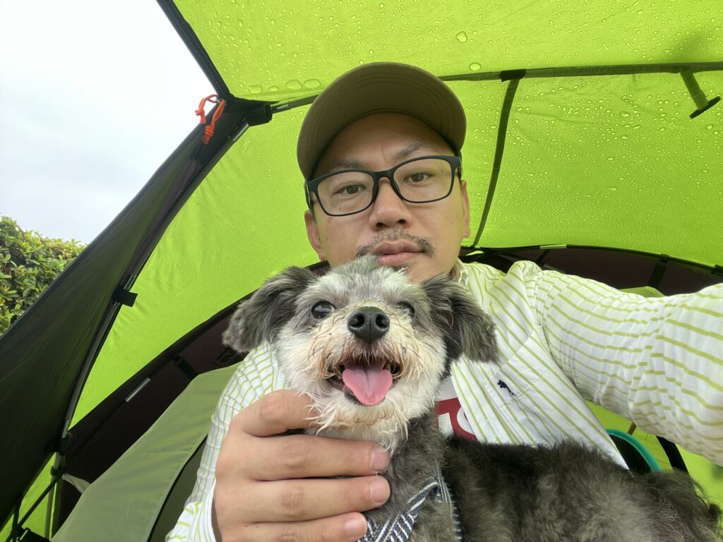 雨の日のキャンプで、愛犬リンと一緒にテント内で過ごす様子を撮影した写真。