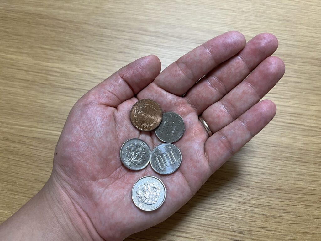 高間木キャンプ場の利用料金として小銭を手に持っている様子。
